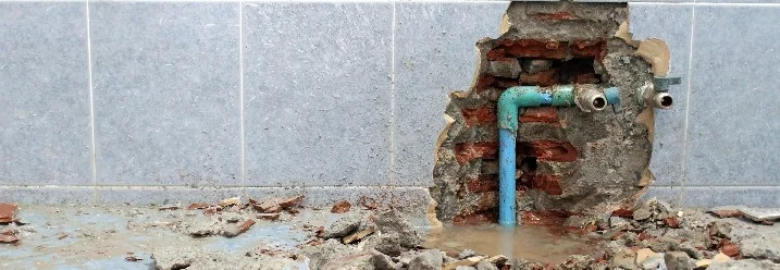 Aufgebrochene Wand mit Wasserrohr